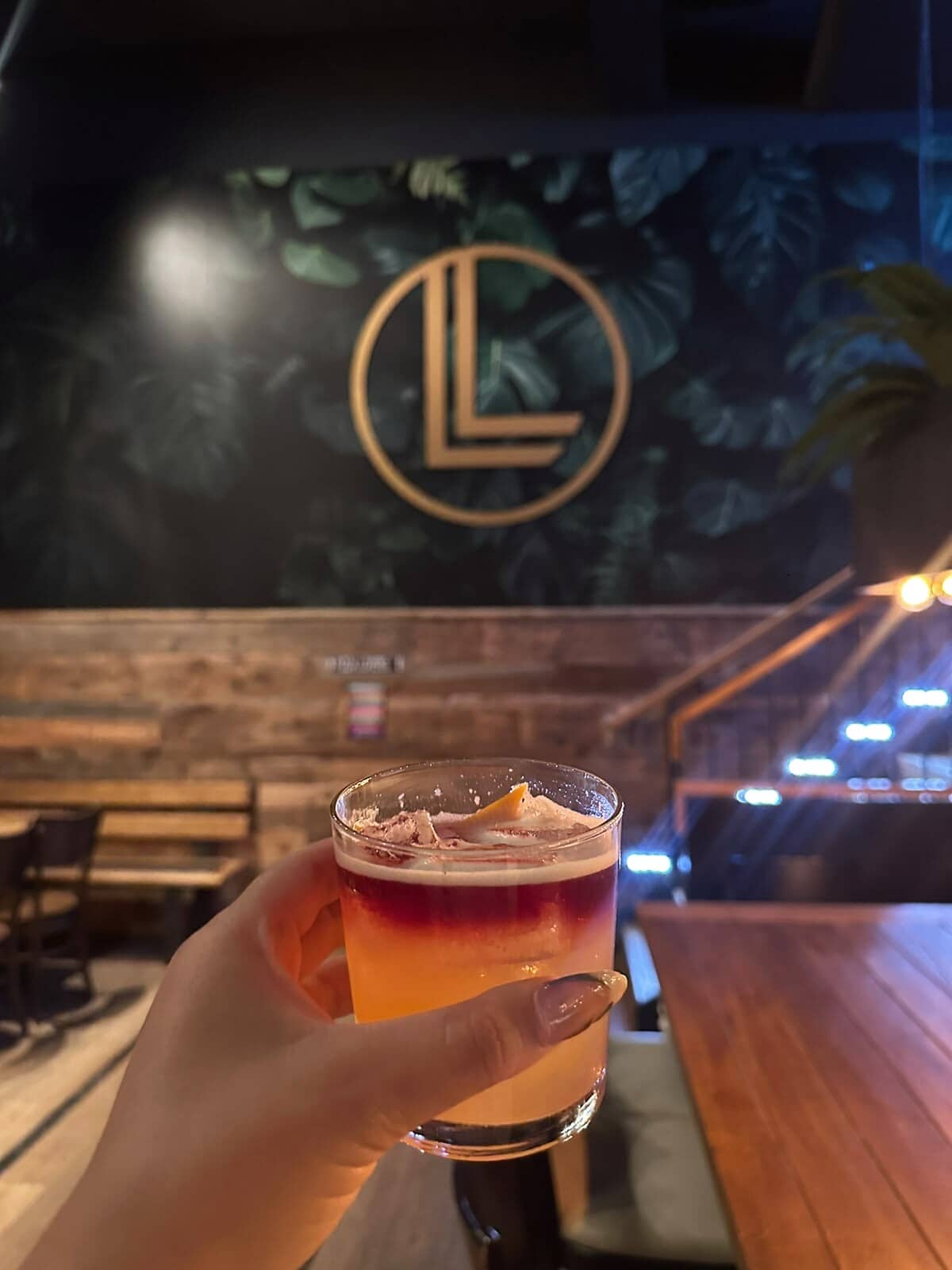 Коктейль в руке, на заднем плане — золотая монограмма Leo's.